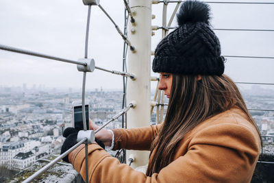 Side view of woman using smart phone against sky