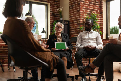 Friends using digital tablet while sitting on chair