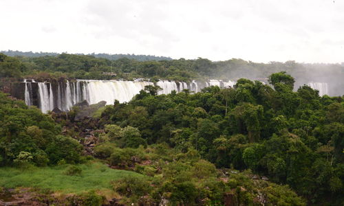 Scenic view of waterfall in forest against sky
