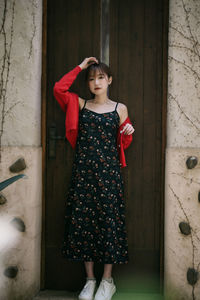 Portrait of young woman standing against wall