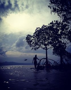 Silhouette man by tree against sea