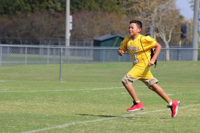 Full length of boy running on playing field