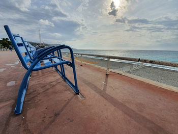 Empty chairs on beach against sky