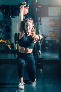 Woman making lunges with kettlebell over the head.