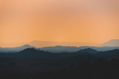 Scenic view of silhouette mountains against orange sky