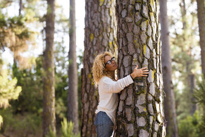 Mature woman hugging tree in forest