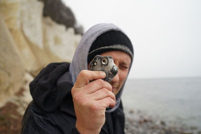 Close-up portrait of man holding camera at beach