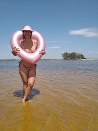 Full length of woman standing in sea against sky