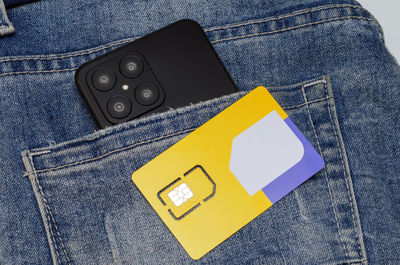 High angle view of smart phone and jeans pocket with wallet with mobile phones on paper