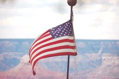 American flag flying at grand canyon against sky