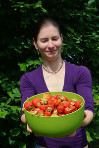 Smiling young woman holding fruits