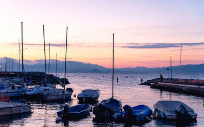 Boats moored at harbor during sunset