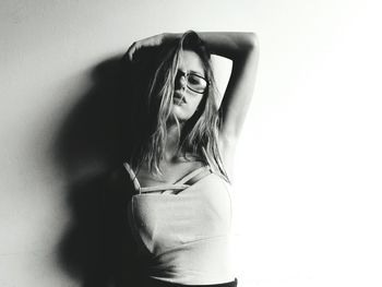 Portrait of young woman standing against wall