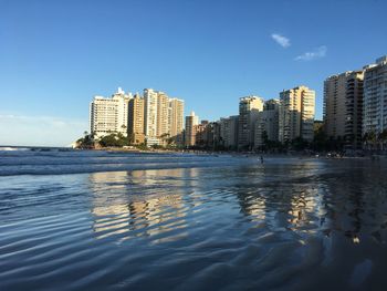 Sea by cityscape against sky