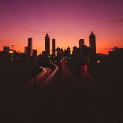 Illuminated buildings in city against sky during sunset