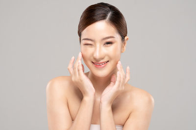 Portrait of a smiling young woman against gray background