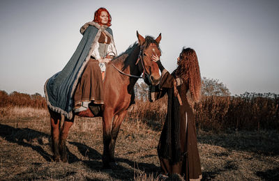 People riding horses on field against sky