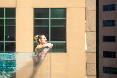 Side view of woman in swimming pool by window
