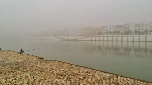 Scenic view of lake against sky in city