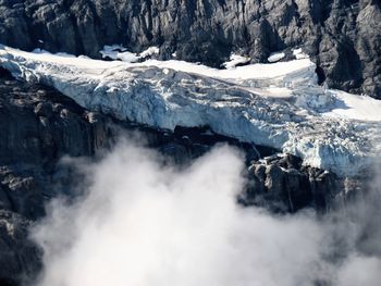 Scenic view of waterfall against mountains during winter