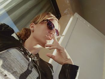 Portrait of young woman holding sunglasses