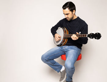 Young man playing guitar against white background