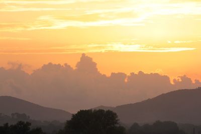 Scenic view of silhouette mountains against orange sky