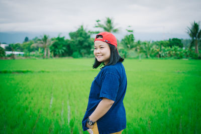 Side view of smiling woman standing on field