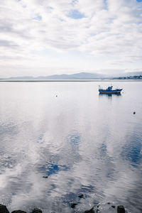 Boat moored on lake against cloudy sky