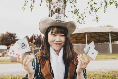 Portrait of smiling young woman playing with cards