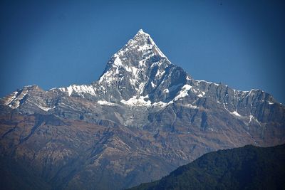 Scenic view of snow covered mountains against blue sky