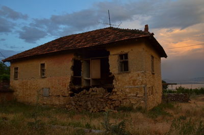 Old house on field against sky