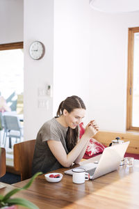 Happy woman looking at laptop computer while sitting in home