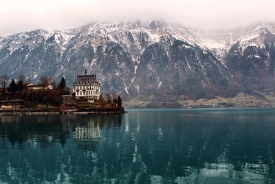 Scenic view of lake by buildings against sky during winter