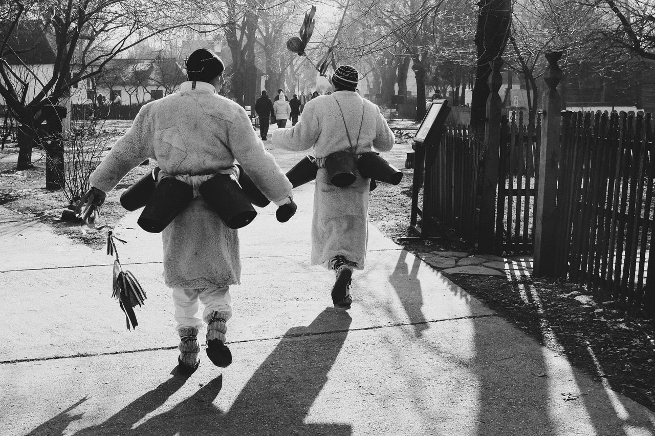 REAR VIEW OF PEOPLE WALKING ON COBBLESTONE STREET