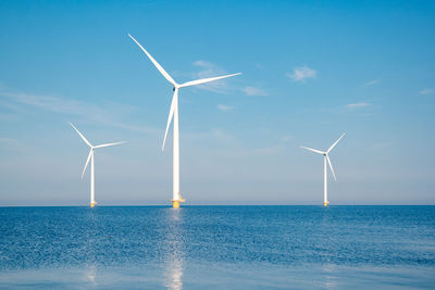 Wind turbines in sea against sky