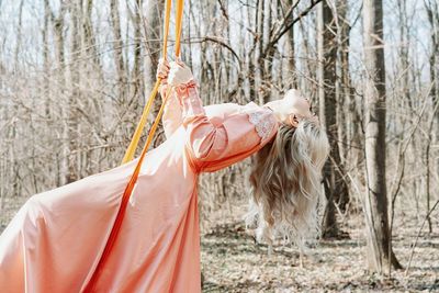 Woman in swing by tree on forest