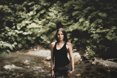 Portrait of young woman standing in forest