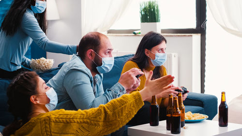 People wearing mask playing game while sitting at home