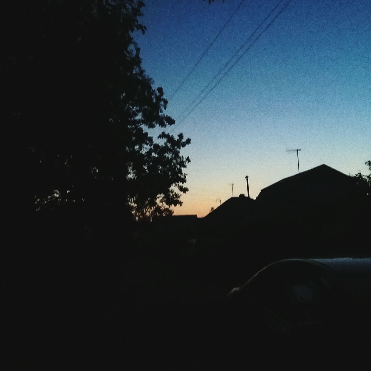 silhouette, tree, clear sky, sunset, copy space, built structure, building exterior, architecture, power line, dark, sky, house, electricity pylon, dusk, low angle view, blue, nature, tranquility, no people, outdoors