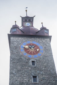 Low angle view of clock tower amidst buildings against sky