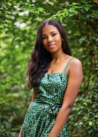 Portrait of young woman standing against plants