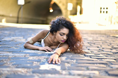 Portrait of beautiful woman lying in city