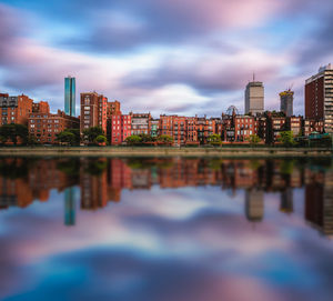 Reflection of buildings in river against sky in city