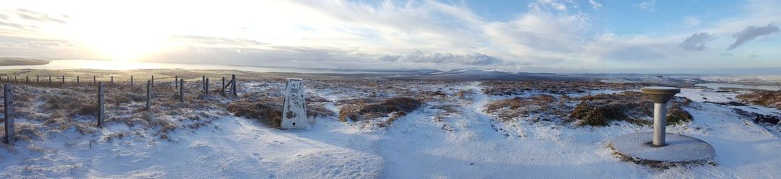 Panoramic view of snow covered land against sky