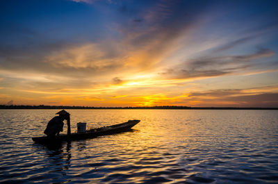 Silhouette man in sea against sky during sunset