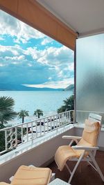 Chairs and table by sea against sky seen from balcony