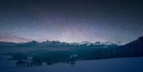 Scenic view of snowcapped mountains against sky at night