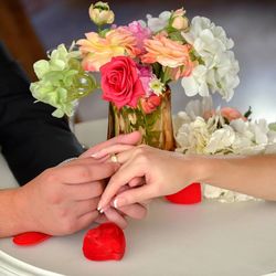 Close-up of groom wearing wedding ring to bride