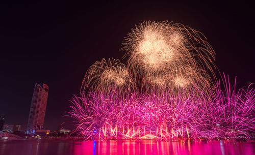 Low angle view of firework display over river at night